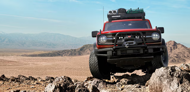 Red Custom Ford Bronco driving on rocks